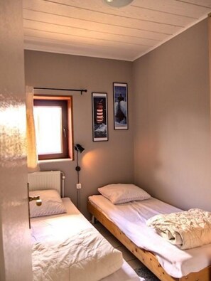 Una camera da letto accogliente e spaziosa con due letti singoli, una finestra vista e due quadri appesi al muro.