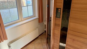 Une pièce avec une fenêtre, un radiateur, une porte en bois et une petite étagère.