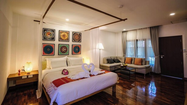 Una camera d'hotel con un letto, un divano, un tavolino e una parete decorata con opere d'arte.