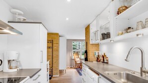 A modern kitchen with white cabinetry, a built-in stove, and a stainless steel sink.