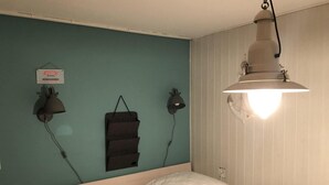 A bedroom with a bed, two wall-mounted lamps, and a hanging towel rack. - Furnished Bungalow With Garden (Sint Maartensvlotbrug)