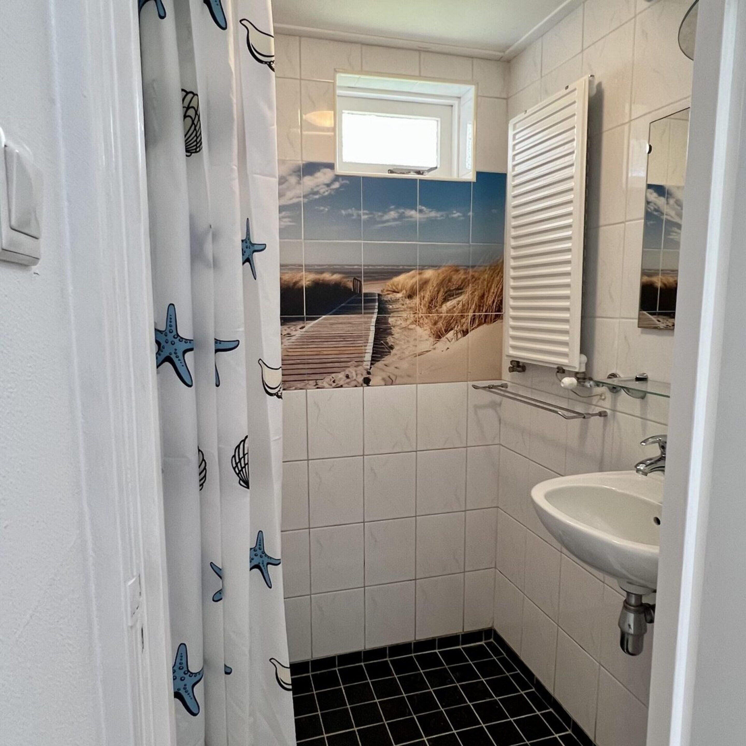A bathroom with a white sink, a mirror, and a shower curtain with starfish designs.