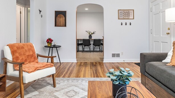 A modern living room with a white sofa, a grey couch, and a wooden floor. There is a dining area with a table and chairs in the background. - Charming 3-bedroom house near downtown Boise with AC, WiFi (Boise)