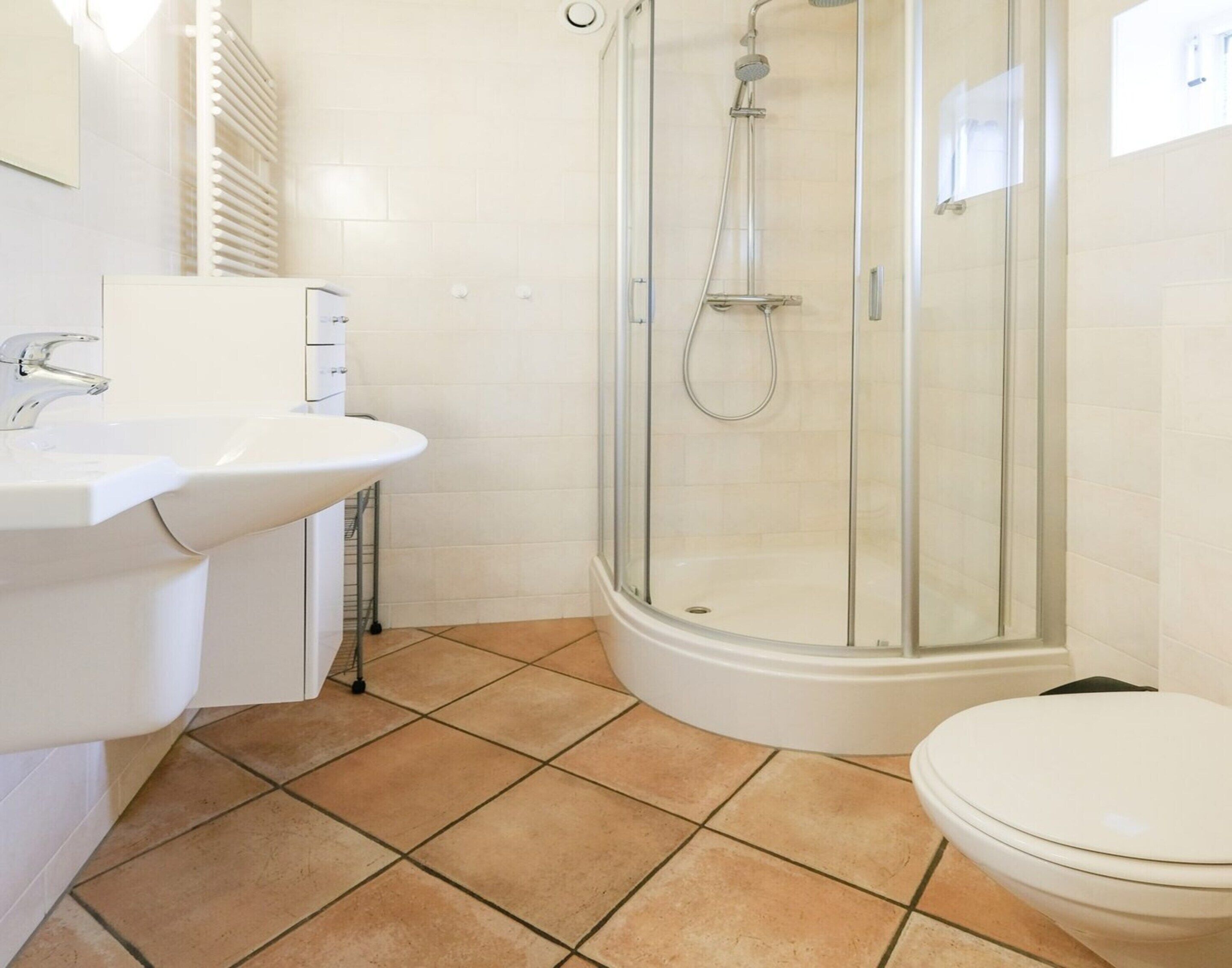 A bathroom with a white sink, a toilet, and a glass-enclosed shower.