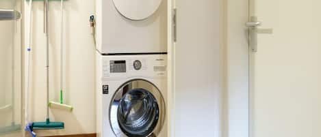 A laundry area with a front-loading washing machine and dryer stacked on top of each other.