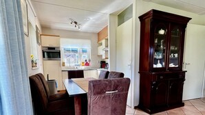 Ein kompakter Wohnbereich mit Küchenzeile, einem Essbereich mit Tisch und Stühlen sowie einem großen Holzschrank.