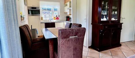 A compact living space with a kitchenette, a dining area with a table and chairs, and a large wooden cabinet.