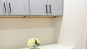 Een badkamer met grijze kastjes, een witte wastafel en een klein vaasje met witte bloemen.