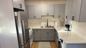 Een moderne keuken met grijze kastjes, een roestvrijstalen koelkast, een spoelbak, een fornuis en een wasmachine.