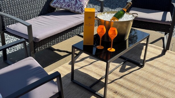 Een tafel met een fles Veuve Clicquot champagne, twee glazen en een doos.