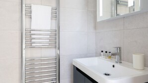 A modern bathroom with a chrome towel rack, a white sink, and a mirror above it.