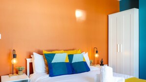 A hotel room with a bed, white wardrobe, and two bedside tables with lamps.