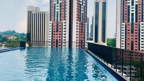Ein modernes Hochhaus mit einem Schwimmbecken im Vordergrund.