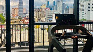 Blick von einem Balkon mit Laufband auf eine Stadtlandschaft mit Hochhäusern und einem markanten Turm.