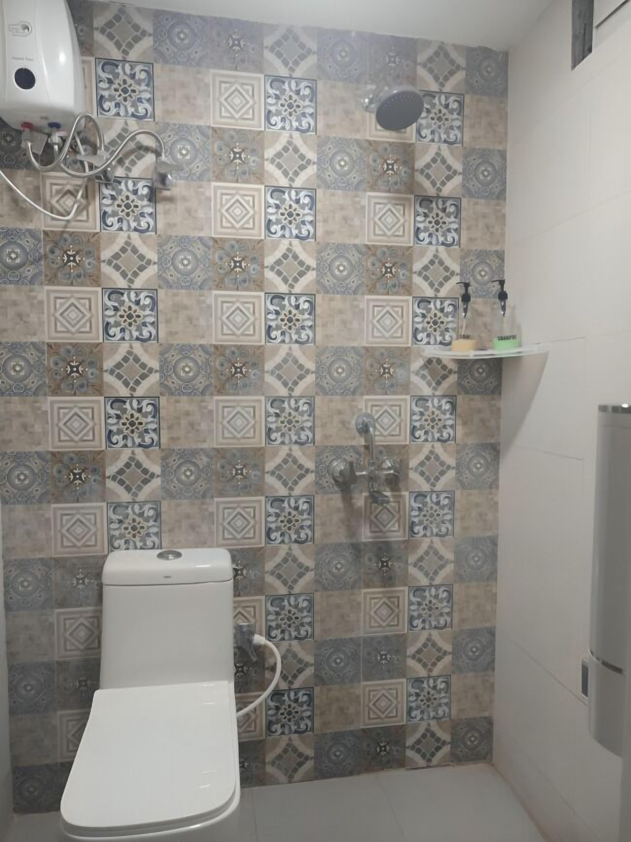 A bathroom with a toilet, a shower, and a hand dryer.