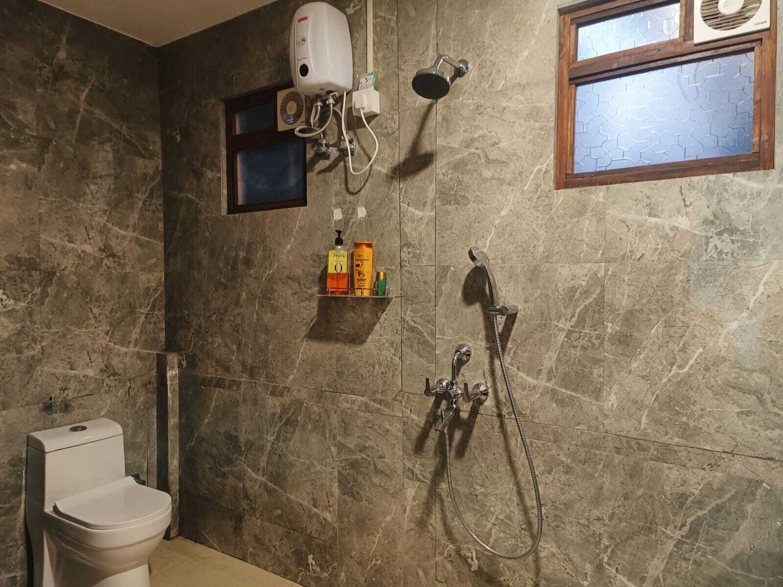 A bathroom with a toilet, a shower, and a window.
