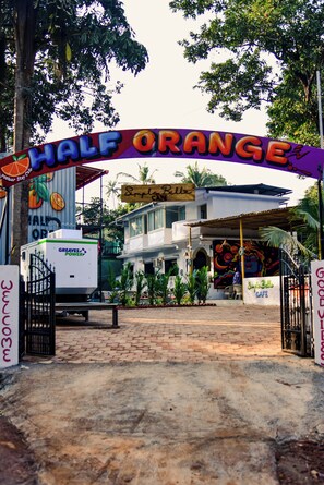 A building entrance with a colorful archway labeled "HALF ORANGE" and a sign that reads "WELCOME." - Half Orange (Vagator)