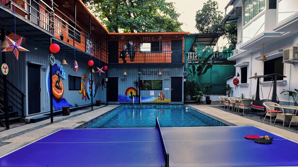 A pool table in an outdoor area with a mural on the wall behind it. - Half Orange (Vagator)
