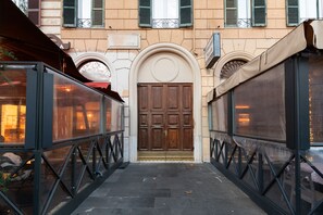 A narrow alleyway with a large wooden door at the end, flanked by glass enclosures with metal frames. - Esquilino Lightsome Apartment (Roma)
