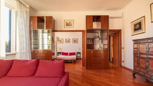 A room with a red sofa, wooden cabinets, a bed with red pillows, and a dresser.