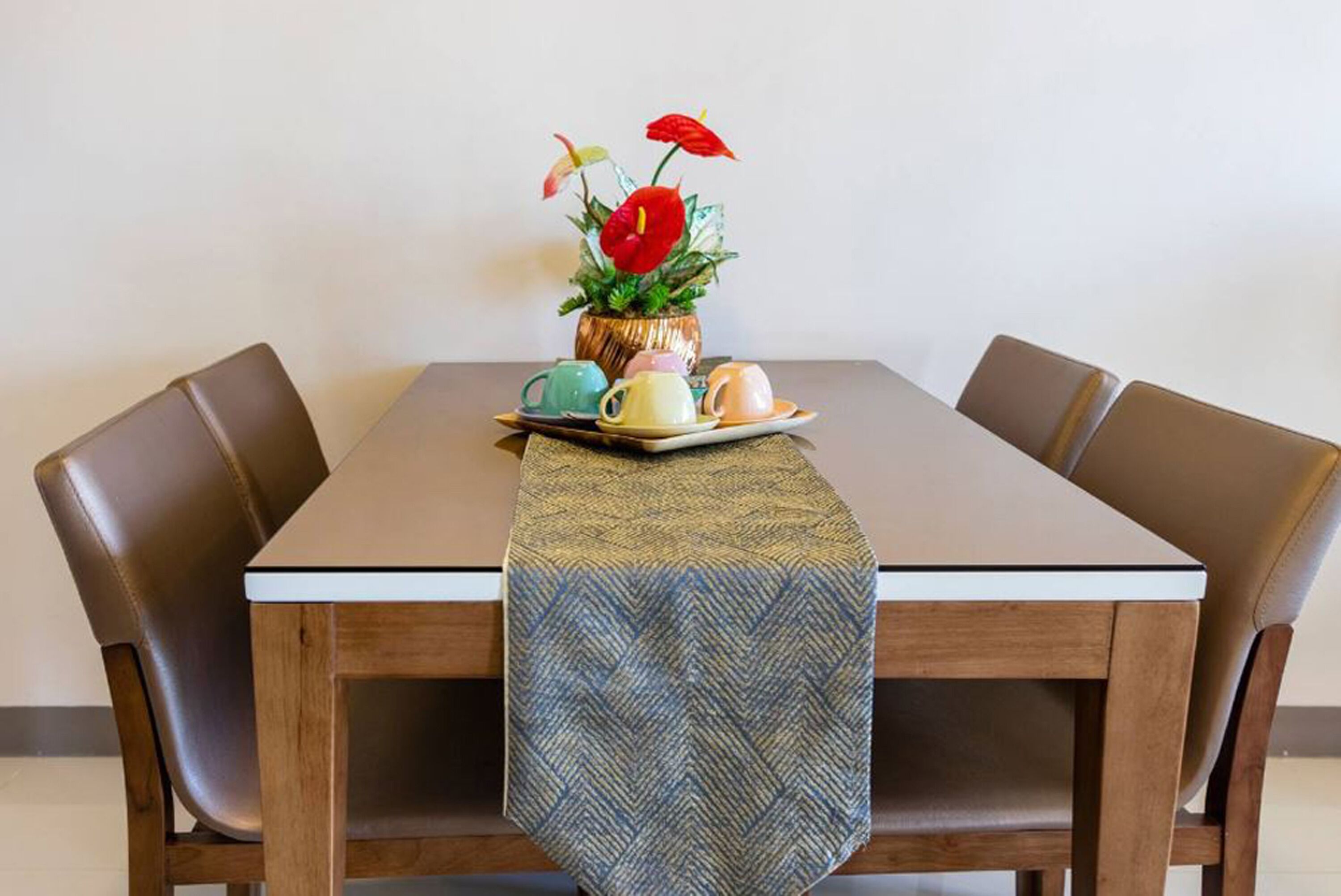 A dining table with a herringbone tablecloth, a floral centerpiece, and a set of teapots.
