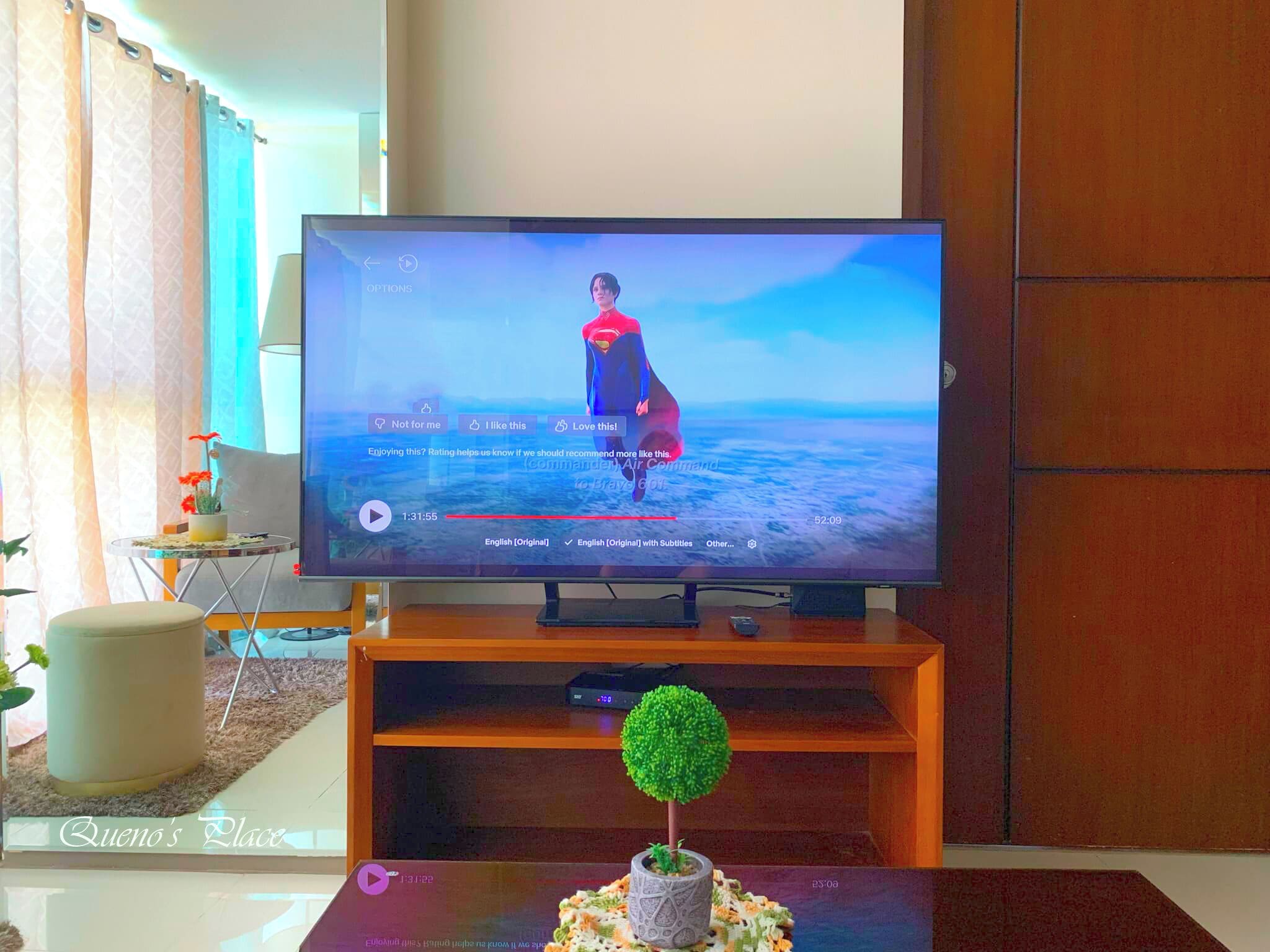 Una TV a schermo piatto su un supporto in legno in un soggiorno con vista sull'oceano.