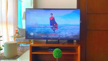 Una TV a schermo piatto su un supporto in legno in un soggiorno con vista sull'oceano.