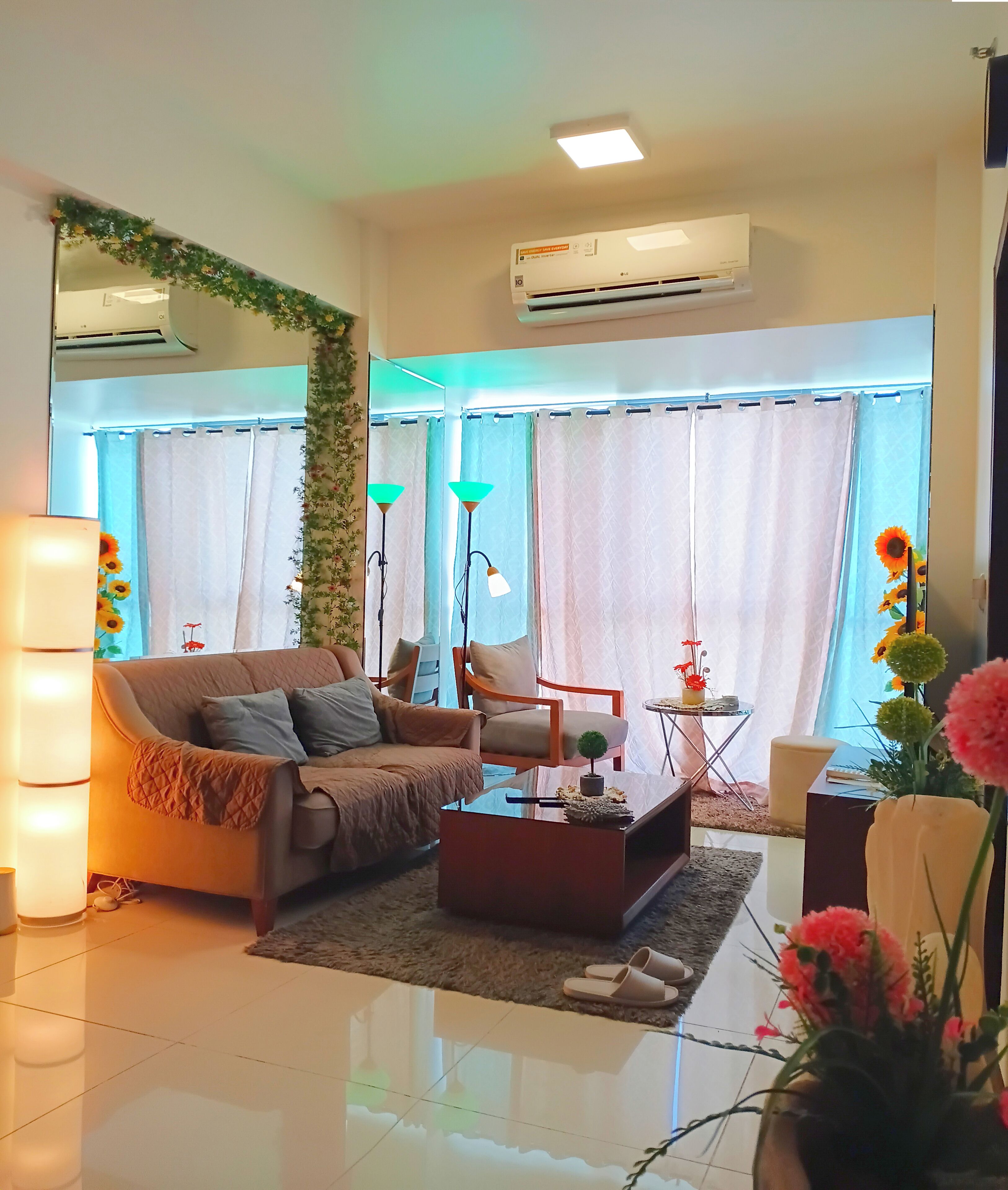 A modern living room with a sofa, armchair, coffee table, and decorative plants.