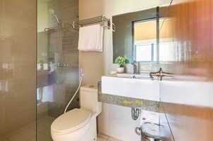 A modern bathroom with a glass-enclosed shower, a white toilet, and a sink with a granite countertop.