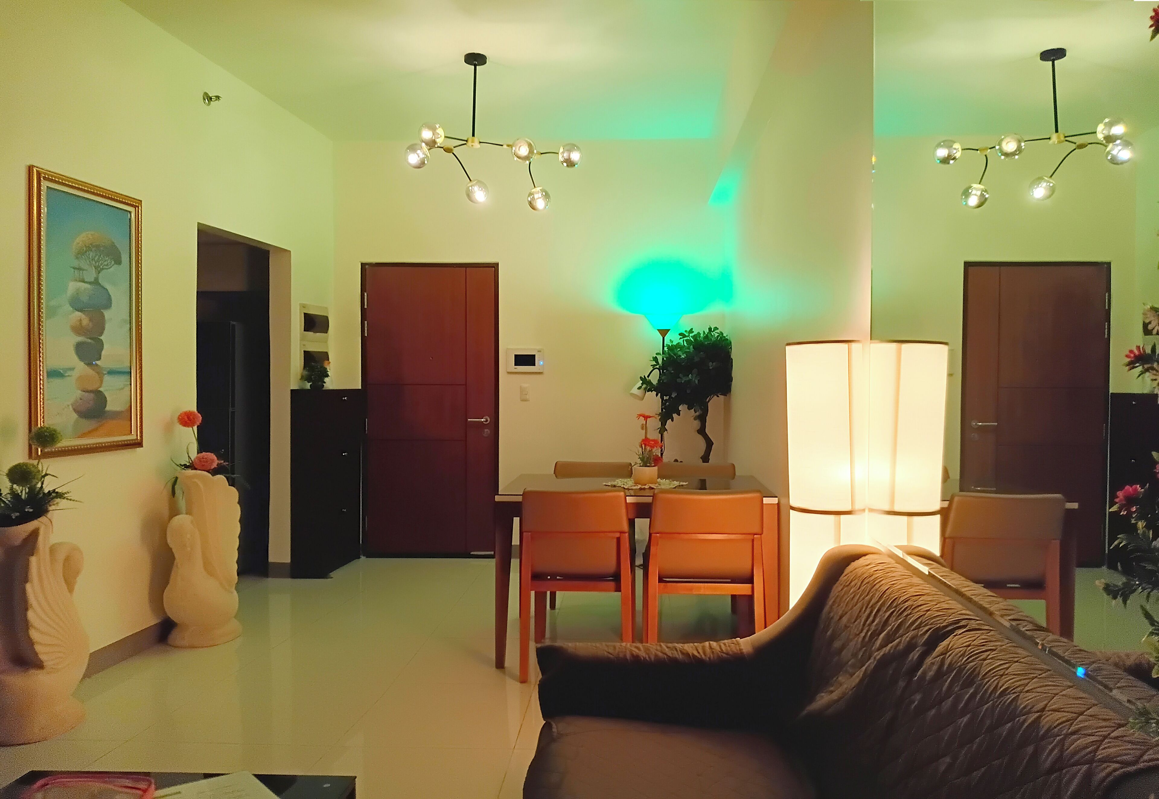 Una sala de estar con sofá, una mesa de comedor con sillas, una lámpara y un candelabro.