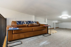 A modern living room with a brown leather sofa, a small side table, and a white lamp. - West Vail Matterhorn Condo - Steps to Bus (Vail)