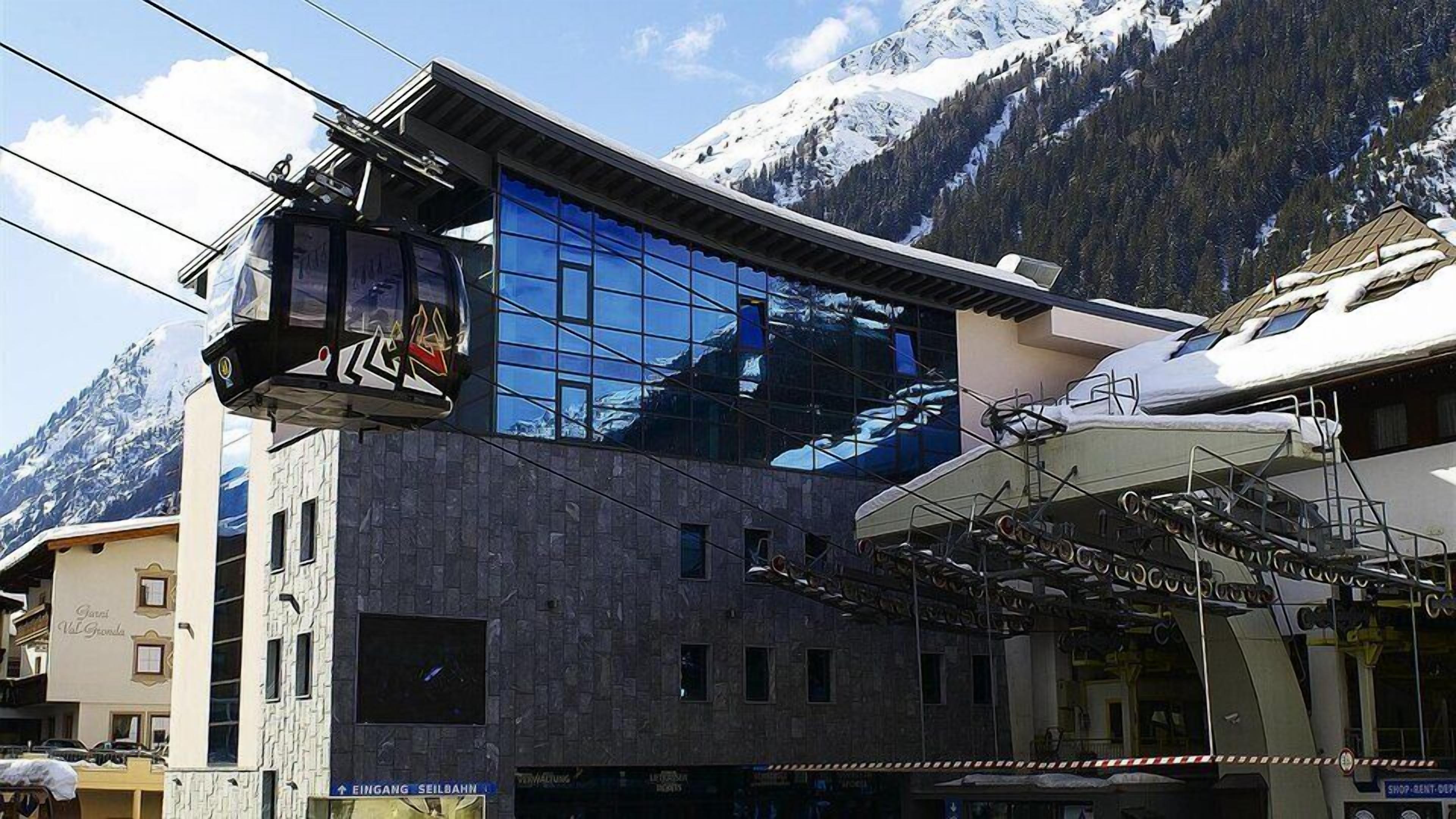 A modern building with a glass facade reflecting the surrounding mountains.