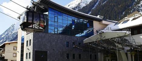 A modern building with a glass facade reflecting the surrounding mountains.