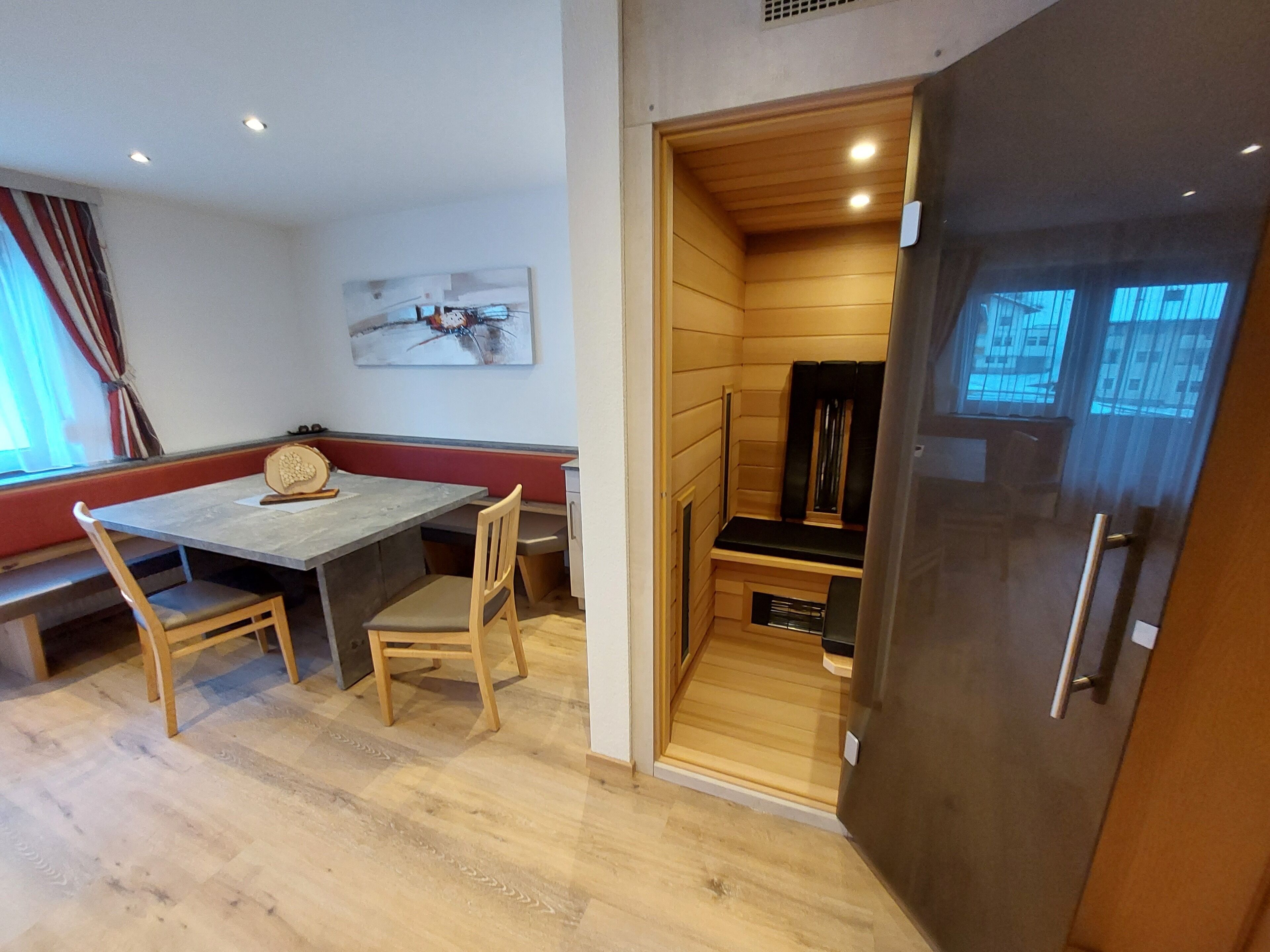 Une pièce compacte comprenant une table à manger en bois, deux chaises, un banc et un sauna intégré.