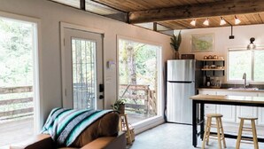 Una cocina moderna con una isla central, taburetes de madera y un refrigerador.