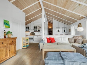 A spacious loft with high ceilings, a kitchen area, and a cozy seating area with a sofa and a bed.