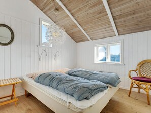 Ein Zimmer mit einem Bett, einem Sessel, einem Spiegel und einem Fenster.