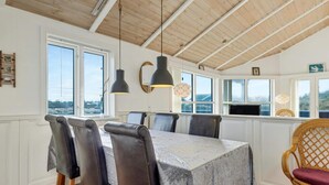 Ein Essbereich mit Tisch und Stühlen, großen Fenstern und Meerblick.