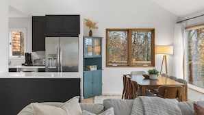 A modern kitchen with dark cabinets, a central island, and a dining area with a table and chairs.