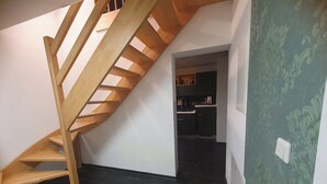 A modern interior with a wooden staircase leading to a kitchen area.