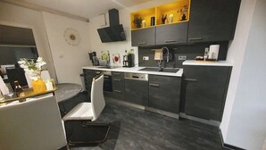 A modern kitchen with dark cabinets, a white countertop, and a built-in oven.