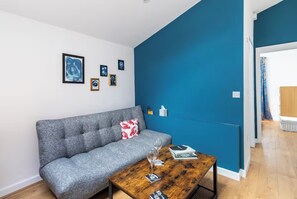 A modern living room with a grey sofa, a wooden coffee table, and a blue accent wall. - Windsor Home with Free Parking (Windsor)