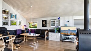 Ein geräumiges Wohnzimmer mit einer schwarzen Couch, Holzstühlen, einem Couchtisch und einem Kamin.