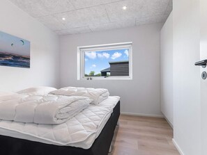 A bedroom with a bed, a window with a view of a building, and a painting on the wall. - 5 Star Holiday Home in Lokken (Lokken)