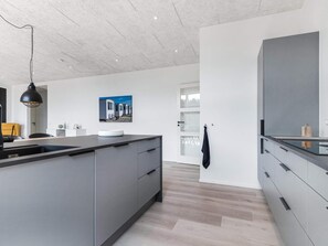 A modern kitchen with a central island, grey cabinetry, and a pendant light. - 5 Star Holiday Home in Lokken (Lokken)