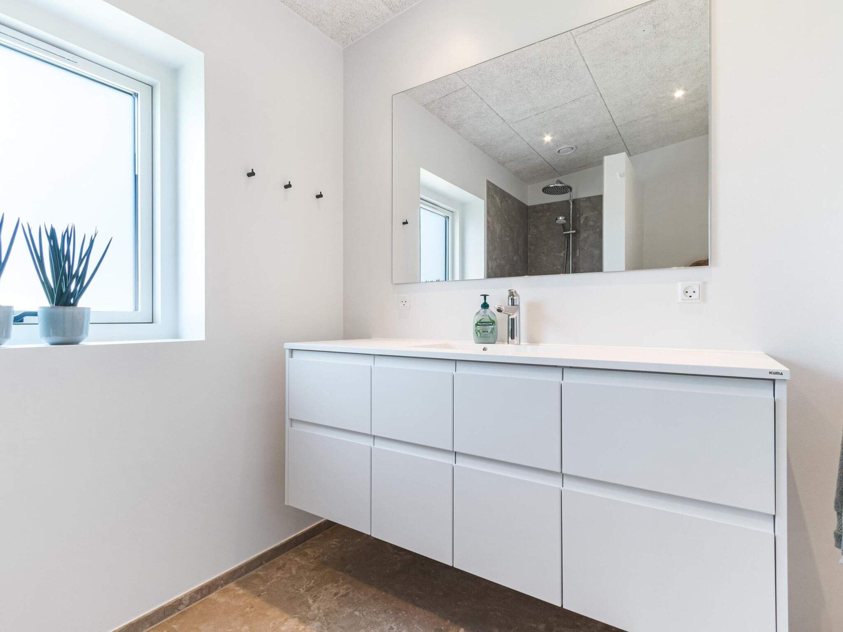 A bathroom with a white vanity, a mirror, and a shower.