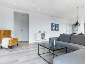 A modern living room with a sofa, armchair, and coffee table. - 5 Star Holiday Home in Lokken (Lokken)