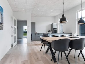 A modern kitchen with a central island, black chairs, and pendant lighting.