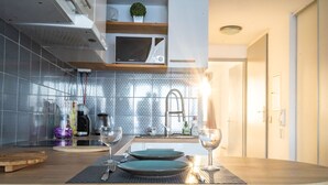 A modern kitchen with a wooden countertop, two green plates, and two wine glasses. - [Vue Imprenable] Appartement Rénové Front de Mer (Arcachon)