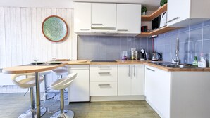 A modern kitchen with white cabinets, a wooden countertop, and a round table with bar stools. - [Vue Imprenable] Appartement Rénové Front de Mer (Arcachon)